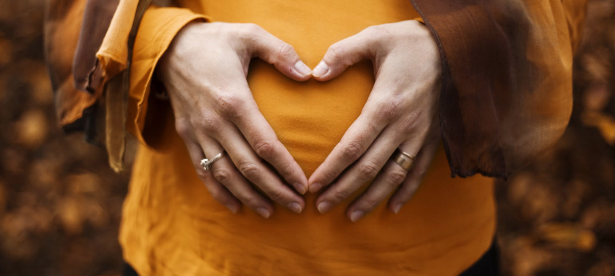Pregnant woman's hands in a heart shape over her belly