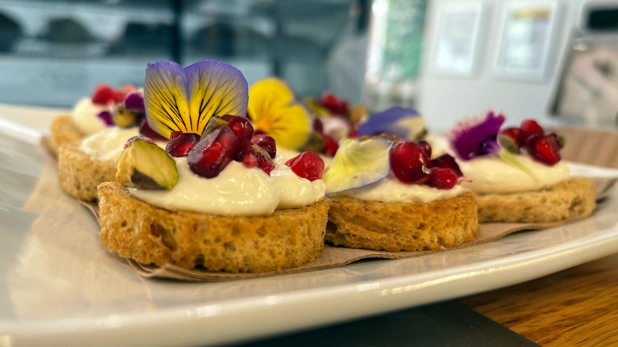 Grazing table with bruschetta topped with whipped cheese, pomegranate and edible flowers