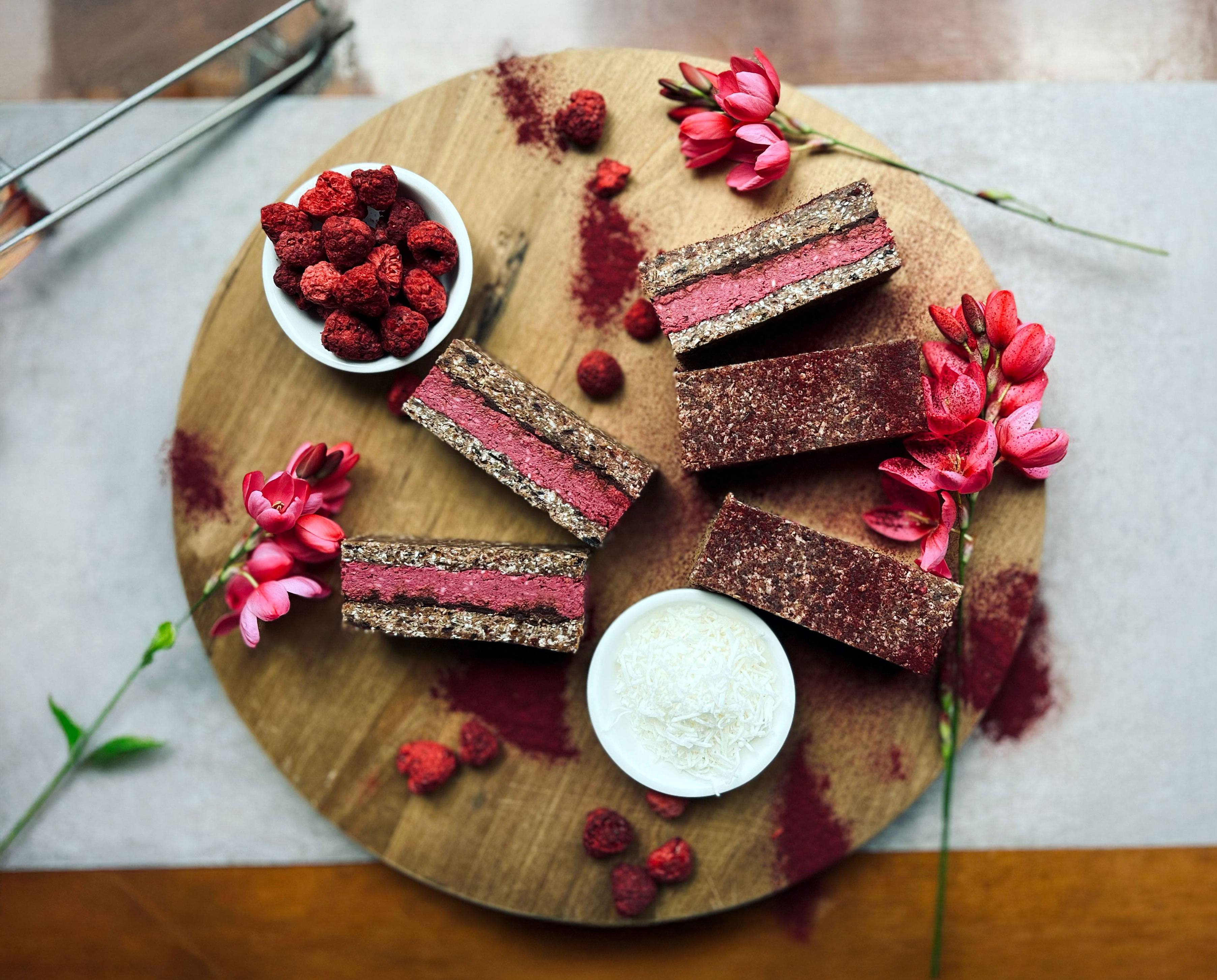 Trophi catering platter with raspberry bars, fresh berries and flowers on a wooden board